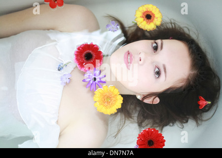 Junge Frau mit Blumen in der Badewanne Stockfoto