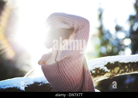 Porträt einer jungen Frau im Schnee bei Gegenlicht Stockfoto