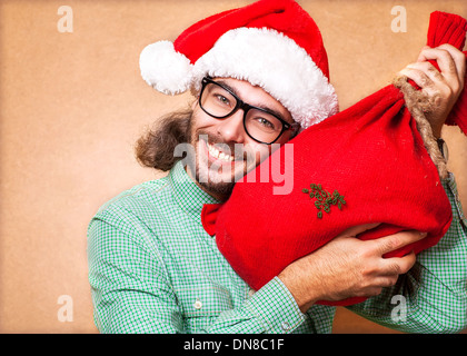 Hipster-Weihnachtsmann mit der Tasche der Geschenke zeigt Klasse Stockfoto