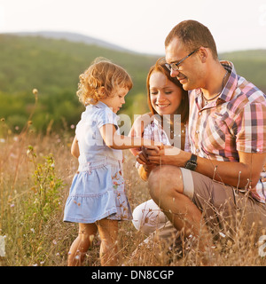 Glückliche Mutter, Vater und Tochter im Sonnenuntergang Stockfoto