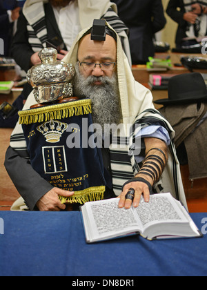 Ein Mann trägt einen Gebetsschal & Gebetsriemen hält eine Tora während der Wochentag morgens Gottesdienste am Lubawitsch-Hauptsitz in New York City Stockfoto