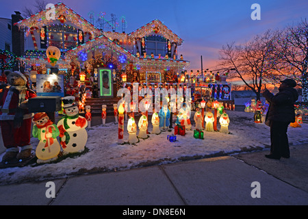 Eine Frau macht ein Foto mit einem iPad von einem Haus in Bayside, Queens, New York mit aufwendigen Beleuchtung für Weihnachten.. Stockfoto