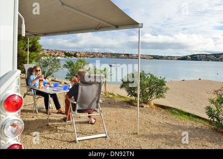 Zwei Urlauber genießen Frühstück und schöne Aussicht neben ihrem Wohnmobil auf einem Campingplatz in Trogir, Kroatien Stockfoto