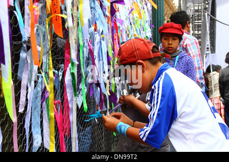 LA PAZ, Bolivien, 20. Dezember 2013. Ein Junge bindet eine Botschaft der Hoffnung zu einem Drahtzaun auf einer Veranstaltung in Plaza Murillo zur Feier der Einführung der ersten Kommunikationssatelliten Boliviens. Bildnachweis: James Brunker / Alamy Live News Stockfoto