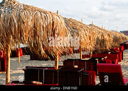 Sonnenschirme in den Strahlen der untergehenden Sonne, Sonnenliegen invertiert - 2 Stockfoto