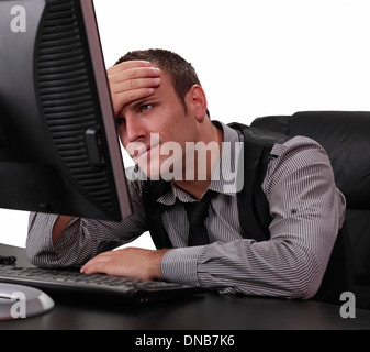 Unglückliche junge Geschäftsmann vor seinem Computer im Büro. Stockfoto