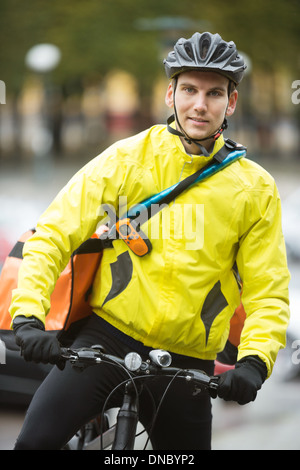 Junge männliche Radfahrer mit Lieferung Kuriertasche auf Straße Stockfoto