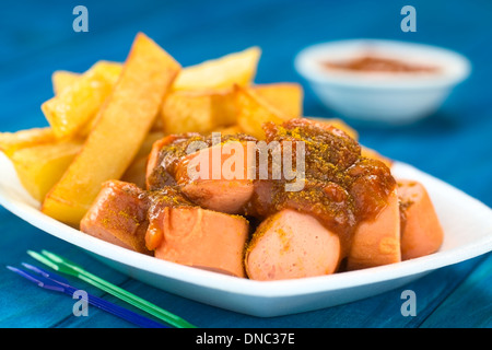 Deutsche Fast-Food genannt Currywurst serviert mit Pommes Frites auf einem Einweg-Teller mit Partei-Gabeln in der front Stockfoto