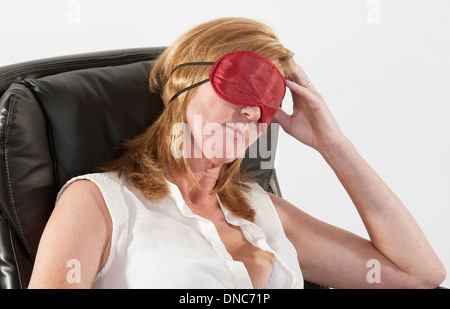 Frau trägt Augenmaske schlafen in einem Bürostuhl Stockfoto