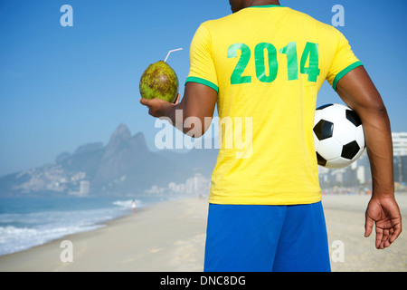 Brasilianischer Fußballspieler tragen Hemd 2014 in Brasilien Farben halten Fußball trinken Kokosnuss Rio De Janeiro Stockfoto