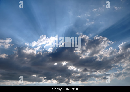 Die Sonnenstrahlen, die durch dunkle Wolken Stockfoto