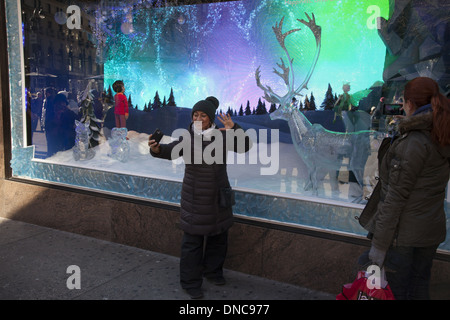 Frau fotografiert sich selbst vor den Weihnachten Fenstern an Lord & Taylor Dept Store auf der 5th Ave, in New York City. Stockfoto