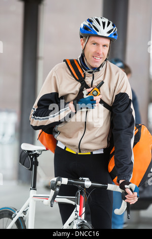Männliche Radfahrer mit Kuriertasche mit Walkie-Talkie Stockfoto