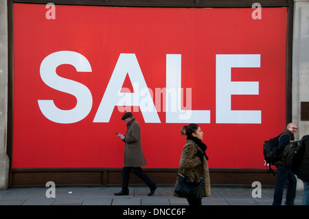 London. Weihnachten 2013. Einkaufen. Vertrieb. Menschen passieren vor einem riesigen Verkaufsschild in einem Schaufenster in der Regent Street Stockfoto