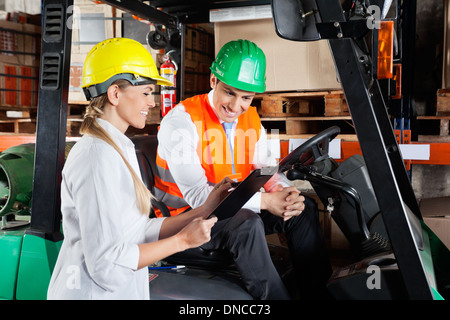 Vorgesetzten zeigen Zwischenablage Kollegen sitzen In Gabelstapler Stockfoto