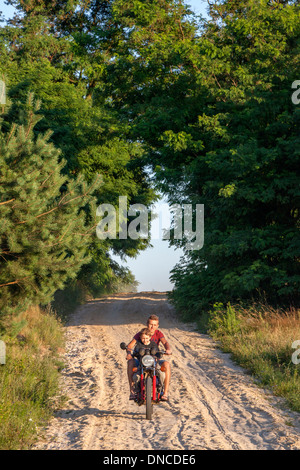 Polnische Jugendliche fahren Motorrad, sandigen Landstraße mit Nachbarsjungen Reiten entlang Alter 18 und 8. Zawady Zentralpolen Stockfoto