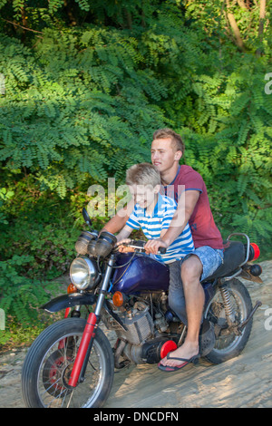 Junge, Reiten auf einem polnischen Jugendlichen Motorrad Reisen über einen geschotterten Land Straße Alter 18 und 10. Zawady Zentralpolen Stockfoto