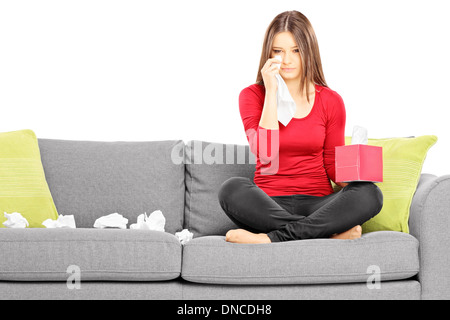 Traurige junge Frauen sitzen auf einer Couch und wischte ihre Augen vom Weinen Stockfoto