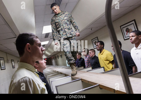 Ein US-Marine wacht über neu angekommenen Rekruten, wie sie ihre Ausrüstung bei Empfang im Marine Corps zu rekrutieren Depot Parris Island ab 13 Wochen von Boot Camp 9. Dezember 2013 in Port Royal, South Carolina ausgestellt werden. Die Marines trainieren jährlich etwa 17.000 Rekruten auf Parris Island. Stockfoto