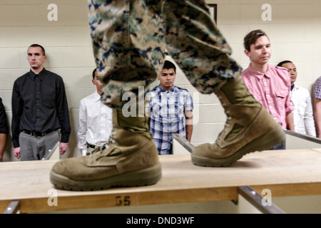 Ein US-Marine wacht über neu angekommenen Rekruten, wie sie ihre Ausrüstung bei Empfang im Marine Corps zu rekrutieren Depot Parris Island ab 13 Wochen von Boot Camp 9. Dezember 2013 in Port Royal, South Carolina ausgestellt werden. Die Marines trainieren jährlich etwa 17.000 Rekruten auf Parris Island. Stockfoto