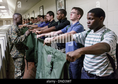 Ein US-Marine wacht über neu angekommenen Rekruten, wie sie ihre Ausrüstung bei Empfang im Marine Corps zu rekrutieren Depot Parris Island ab 13 Wochen von Boot Camp 9. Dezember 2013 in Port Royal, South Carolina ausgestellt werden. Die Marines trainieren jährlich etwa 17.000 Rekruten auf Parris Island. Stockfoto