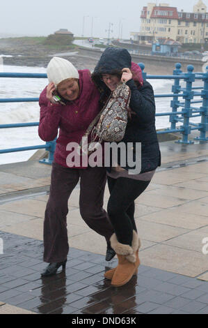 Porthcawl, Wales, UK. 23. Dezember 2013. Zwei Frauen kämpfen gegen die starken fahren Wind und Regen auf der Strandpromenade Porthcawl wie Südwales auf gelbe Warnung bei starkem Regen und Winde bis zu 70 km/h. Das stürmische Wetter war voraussichtlich weit verbreiteten Störungen in ganz Großbritannien. Bildnachweis: Graham M. Lawrence/Alamy Live-Nachrichten. Stockfoto