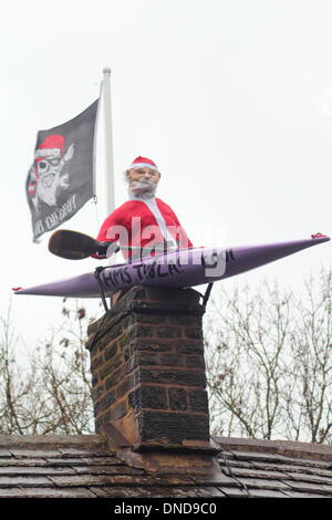 Tideswell, Derbyshire, UK.  23. Dezember 2013.  Santa sitzt in einem Kanu, genannt "HMS Tidza" auf dem Dach des The Anchor Inn, einer Gastwirtschaft 15. Jahrhundert als strömendem Regen und starkem Wind fegen über den Peak District.  Tideswell ist von den lokalen Bewohnern liebevoll als Tidza bezeichnet. Bildnachweis: Deborah Vernon/Alamy Live-Nachrichten Stockfoto