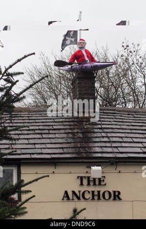 Tideswell, Derbyshire, UK.  23. Dezember 2013.  Santa sitzt in einem Kanu, genannt "HMS Tidza" auf dem Dach des The Anchor Inn, einer Gastwirtschaft 15. Jahrhundert als strömendem Regen und starkem Wind fegen über den Peak District.  Tideswell ist von den lokalen Bewohnern liebevoll als Tidza bezeichnet. Bildnachweis: Deborah Vernon/Alamy Live-Nachrichten Stockfoto