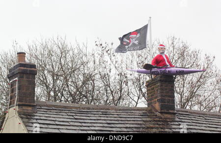 Tideswell, Derbyshire, UK.  23. Dezember 2013.  Santa sitzt in einem Kanu, genannt "HMS Tidza" auf dem Dach des The Anchor Inn, einer Gastwirtschaft 15. Jahrhundert als strömendem Regen und starkem Wind fegen über den Peak District.  Tideswell ist von den lokalen Bewohnern liebevoll als Tidza bezeichnet. Bildnachweis: Deborah Vernon/Alamy Live-Nachrichten Stockfoto