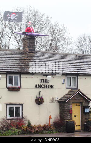 Tideswell, Derbyshire, UK.  23. Dezember 2013.  Santa sitzt in einem Kanu, genannt "HMS Tidza" auf dem Dach des The Anchor Inn, einer Gastwirtschaft 15. Jahrhundert als strömendem Regen und starkem Wind fegen über den Peak District.  Tideswell ist von den lokalen Bewohnern liebevoll als Tidza bezeichnet. Bildnachweis: Deborah Vernon/Alamy Live-Nachrichten Stockfoto