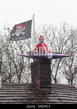 Tideswell, Derbyshire, UK.  23. Dezember 2013.  Santa sitzt in einem Kanu, genannt "HMS Tidza" auf dem Dach des The Anchor Inn, einer Gastwirtschaft 15. Jahrhundert als strömendem Regen und starkem Wind fegen über den Peak District.  Tideswell ist von den lokalen Bewohnern liebevoll als Tidza bezeichnet. Bildnachweis: Deborah Vernon/Alamy Live-Nachrichten Stockfoto