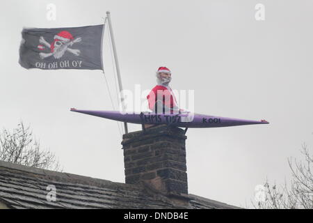 Tideswell, Derbyshire, UK.  23. Dezember 2013.  Santa sitzt in einem Kanu, genannt "HMS Tidza" auf dem Dach des The Anchor Inn, einer Gastwirtschaft 15. Jahrhundert als strömendem Regen und starkem Wind fegen über den Peak District.  Tideswell ist von den lokalen Bewohnern liebevoll als Tidza bezeichnet. Stockfoto