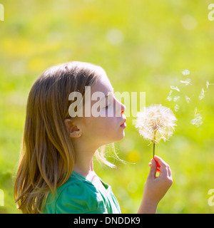 Blonde junge Mädchen bläst Blume Löwenzahn in der grünen Wiese im freien Profilansicht Stockfoto