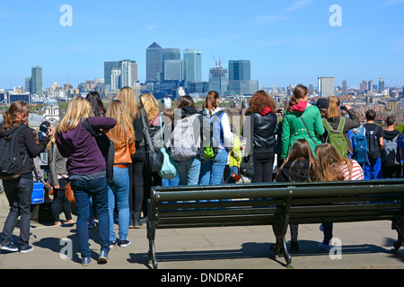 Eine Gruppe von Mädchen und Jungen sieht die Studenten einen Bildungsbesuch im Greenwich Park & Observatory mit Blick auf Canary Wharf am sonnigen Frühlingstag London UK Stockfoto