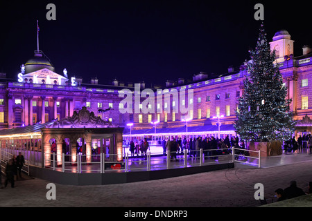 Leute beobachten Eisläufer Somerset House Weihnachtsbaum & Flutlicht Historische Fassade in der Nacht in temporären Winterhof Eislaufen Eisbahn London Großbritannien Stockfoto