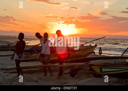 Morondava, Madagaskar. 23. Dezember 2013. Lokale Dorfbewohner Chat neben Kanus am Strand von Morondava, West-Madagaskar, 22. Dezember 2013. © Li Jing/Xinhua/Alamy Live-Nachrichten Stockfoto