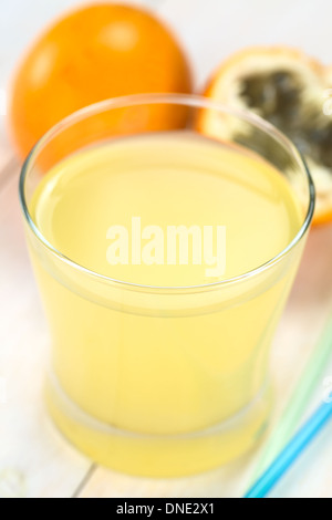 Frischer Saft gemacht süße Granadilla oder Grenadia (lat. Passiflora Ligularis) im Glas mit einem Strohhalm auf der Seite Stockfoto
