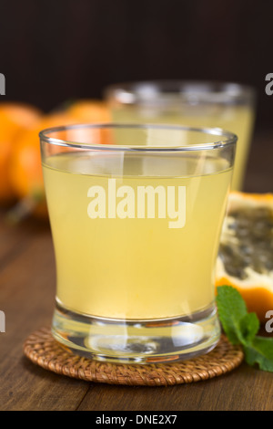Frischer Saft gemacht süße Granadilla oder Grenadia (lat. Passiflora Ligularis) aus Glas mit Granadilla Obst in den Rücken Stockfoto
