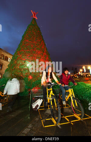 La Paz, Bolivien. 24. Dezember 2013. Einheimischen Pedal auf Fahrrädern verbunden, Batterien, elektrischen Energie für die Beleuchtung auf eine ökologische Weihnachtsbaum im Plaza San Francisco bieten. Der Baum ist mehr als 15m hoch, enthält ca. 50.000 recycelten Kunststoff-Getränkeflaschen und war ein Projekt konzipiert und geplant von der Stadtverwaltung von La Paz. Bildnachweis: James Brunker / Alamy Live News Stockfoto