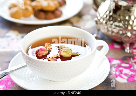 Schwarzer Tee mit Rose Knospen durch einige cookies Stockfoto