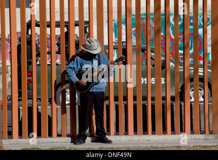 Eine Gitarrist praktiziert in Benito Juarez Park wie eine mexikanische Armee Patrouille vorbei fährt 17. Januar 2009 in Juarez, Mexiko. Die schwer bewaffneten Militärs Patrouillen die Stadt zu helfen, die Gewalt in den laufenden Drogenkrieg Einhalt zu Gebieten, die bereits mehr als 40 Menschen seit Beginn des Jahres vergeben. Mehr als 1600 Menschen starben in Juarez im Jahr 2008 macht die heftigste Stadt zu Juarez in Mexiko. Stockfoto