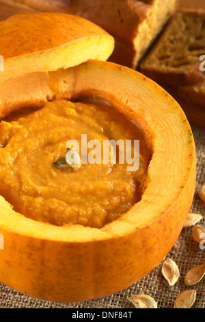 Frische, cremige Kürbissuppe serviert in einem Kürbis, garniert mit Kürbiskernen (selektiven Fokus, Fokus auf den Samen) Stockfoto