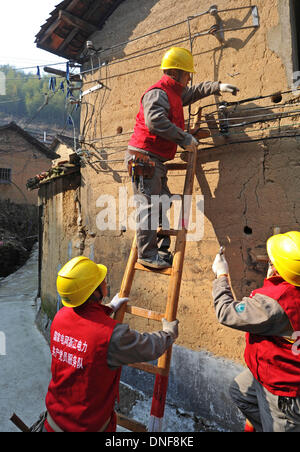 Wuyi, China Zhejiang Provinz. 25. Dezember 2013. Elektriker überprüfen eines Landwirts Ferienhaus am Liuconghu Dorf des Wuyi County, Ost-China Zhejiang Provinz, 24. Dezember 2013. Eine Reihe von Dienstleistungen wurden regelmäßig durch ein Regierungsteam des Wuyi County zugunsten der Landbewohner angeboten. © Tan Jin/Xinhua/Alamy Live-Nachrichten Stockfoto