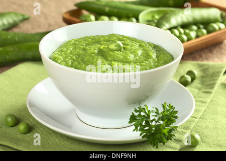 Frische grüne Erbsensuppe mit Erbse Samen und Schoten um (selektiven Fokus, Fokus auf der Erbse in der Mitte der Suppe) Stockfoto