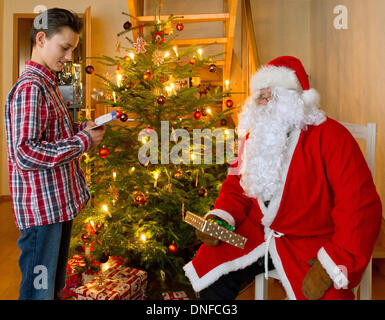 Sieversdorf, Deutschland. 24. Dezember 2013. Zwölf Jahre alte Dan liest ein Gedicht an den Weihnachtsmann neben einem Weihnachtsbaum in Sieversdorf, Deutschland, 24. Dezember 2013. Foto: Patrick Pleul - Model Released/Dpa/Alamy Live News Stockfoto