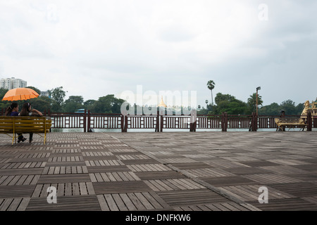 Junges Paar sitzen unter Dach an Deck neben Kandawgyi See, Yangon, Myanmar im Oktober 2013 unter einem grauen Himmel. Stockfoto