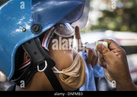 Bangkok, Thailand. 26. Dezember 2013. Eine protestierende bekommt seine Augen ausgespült, nachdem er von Tränengas während eines Aufstandes im Thai Japan Stadium in Bangkok getroffen wurde. Tausende von Anti-Regierungs-Demonstranten strömten in die Gegend um das Thai Japan-Stadion zu versuchen, die Zeichnung der Stimmzettel Listennummern von der Wahlkommission zu verhindern, die die Reihenfolge bestimmt, in der Kandidaten auf dem Stimmzettel der 2. Februar Wahl erscheinen. Sie waren nicht in der Lage, ins Stadion zu brechen und Stimmzettel Liste Unentschieden ging als geplant. Bildnachweis: ZUMA Press, Inc./Alamy Live-Nachrichten Stockfoto