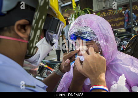 Bangkok, Thailand. 26. Dezember 2013. Ein Sanitäter helfen, eine Frau, die in einem Aufstand im Thai Japan Stadium in Bangkok verletzt wurde. Tausende von Anti-Regierungs-Demonstranten strömten in die Gegend um das Thai Japan-Stadion zu versuchen, die Zeichnung der Stimmzettel Listennummern von der Wahlkommission zu verhindern, die die Reihenfolge bestimmt, in der Kandidaten auf dem Stimmzettel der 2. Februar Wahl erscheinen. Sie waren nicht in der Lage, ins Stadion zu brechen und Stimmzettel Liste Unentschieden ging als geplant. Bildnachweis: ZUMA Press, Inc./Alamy Live-Nachrichten Stockfoto