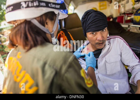 Bangkok, Thailand. 26. Dezember 2013. Ein Medic hilft einem Thai Randalierer erschossen mit einer Kautschuk-Kugel abgefeuert von der Polizei während eines Aufstandes im Thai Japan Stadion in Bangkok. Tausende von Anti-Regierungs-Demonstranten strömten in die Gegend um das Thai Japan-Stadion zu versuchen, die Zeichnung der Stimmzettel Listennummern von der Wahlkommission zu verhindern, die die Reihenfolge bestimmt, in der Kandidaten auf dem Stimmzettel der 2. Februar Wahl erscheinen. Sie waren nicht in der Lage, ins Stadion zu brechen und Stimmzettel Liste Unentschieden ging als geplant. Stockfoto