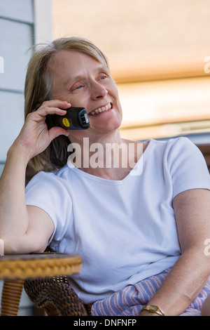 Applying Frau draußen, Lächeln, reden über ein schnurloses Telefon Stockfoto